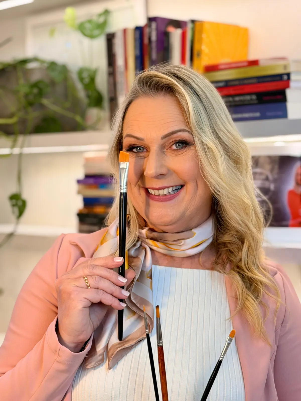 Retrato de Marisa Reckziegel sorrindo, com um pincel na mão